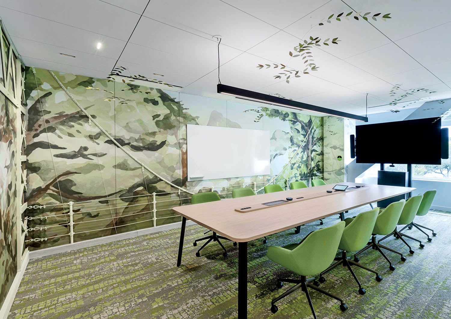 A conference room with a large screen and green chairs.