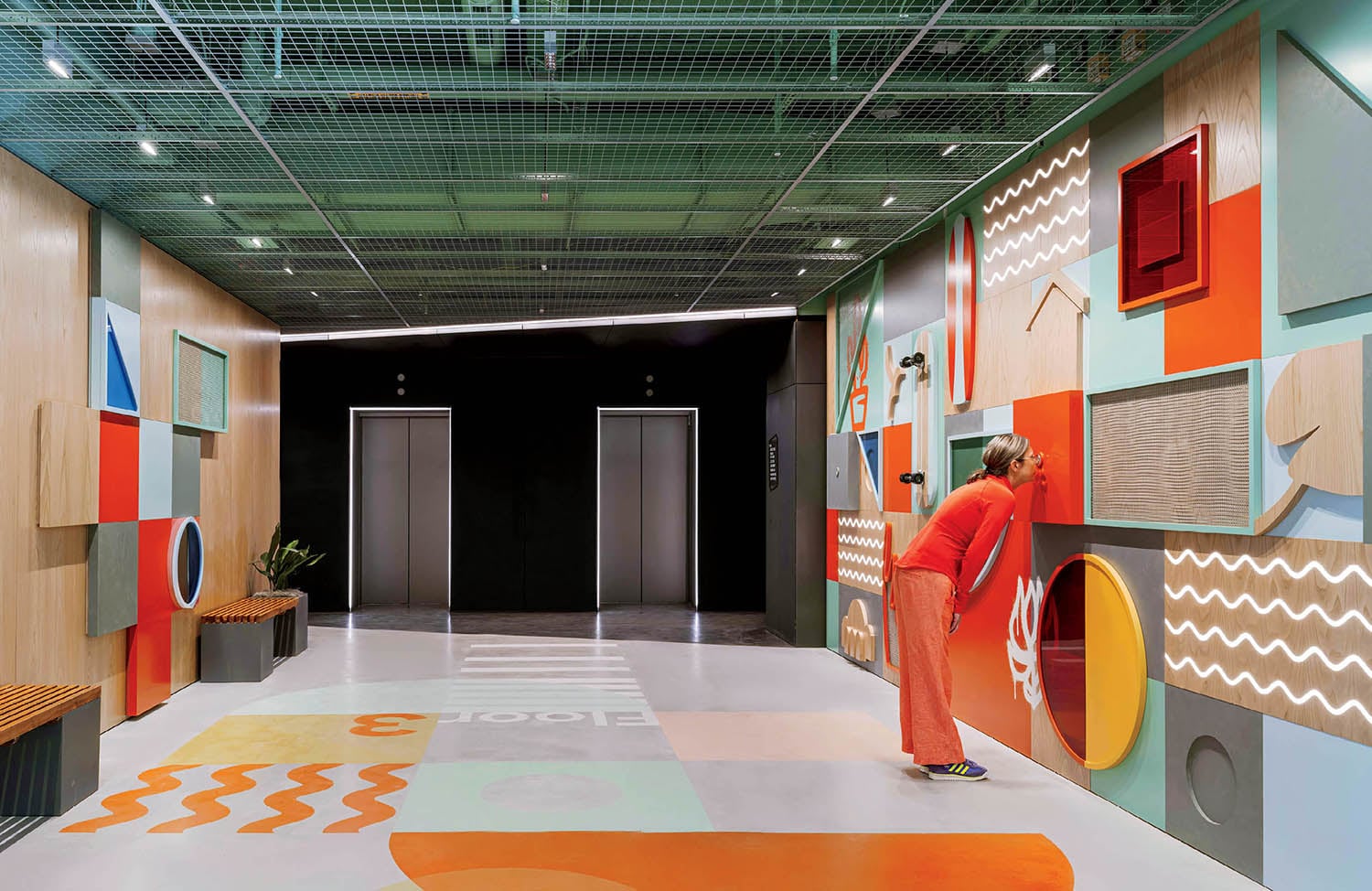 A woman is walking through a colorfully painted hallway.