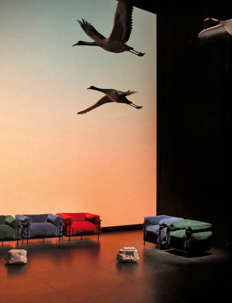 A room with a couch, chairs, and a bird flying overhead.