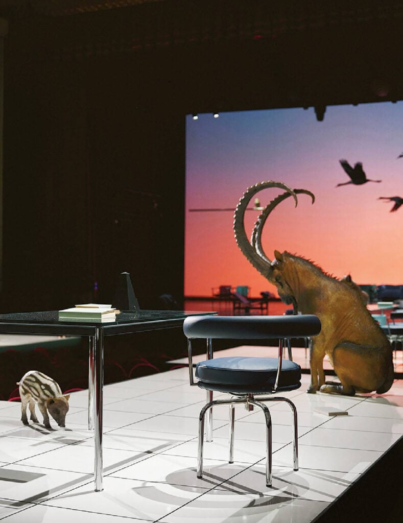 A dinosaur is sitting on a table with chairs.