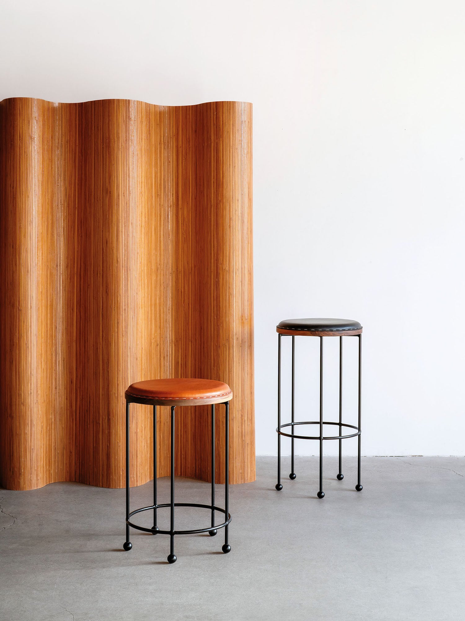 Two stools in front of a wooden wall.