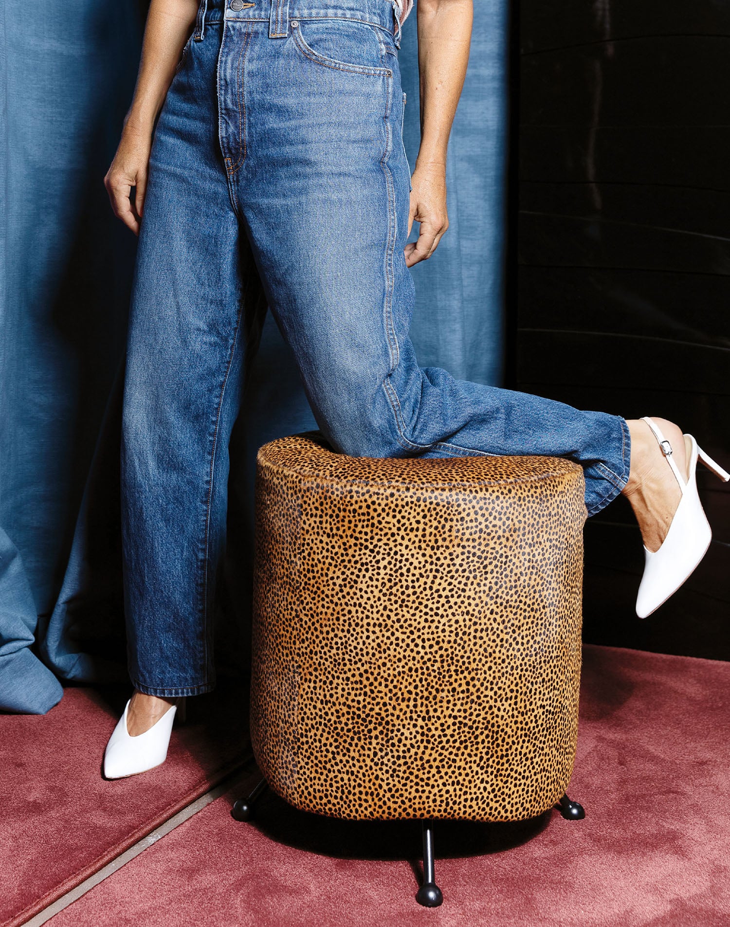 A woman in a white shirt and jeans is standing on a leopard prin.