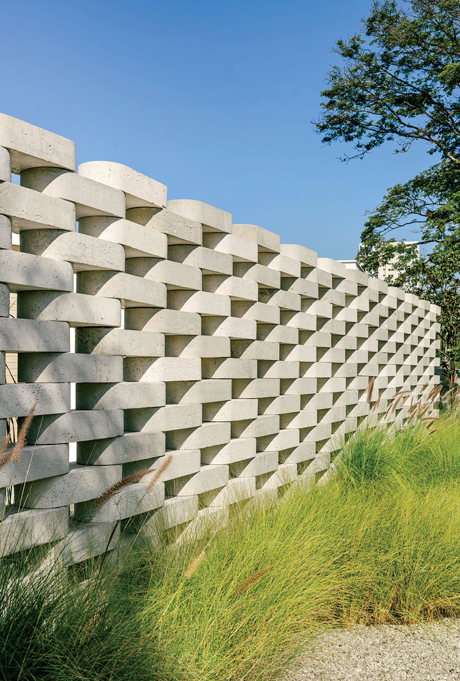 A concrete wall with grass growing in front.
