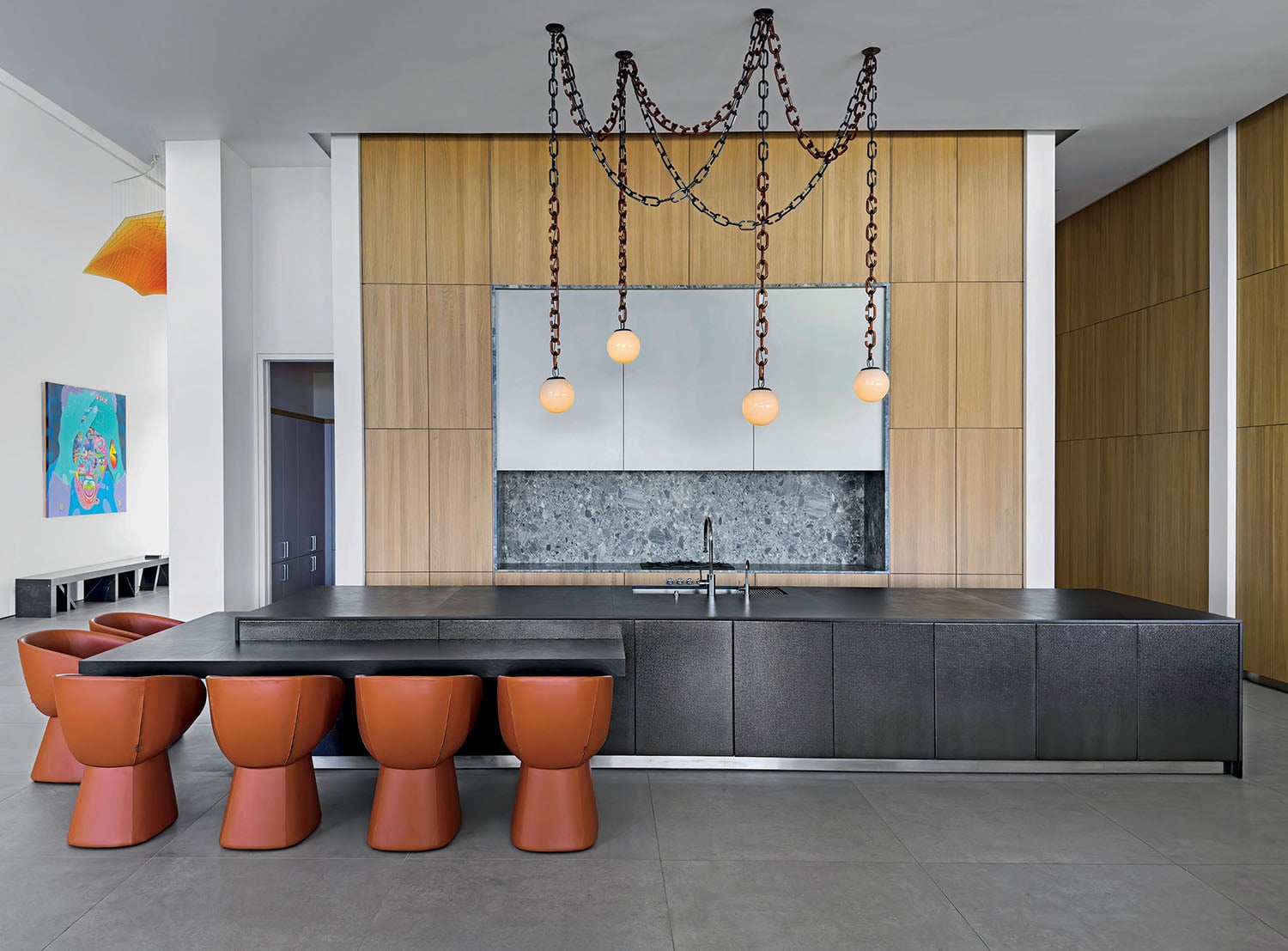 A kitchen with a large island and orange stools.