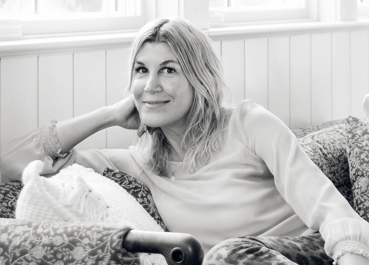 A woman sitting on a couch with her hand on her chin.