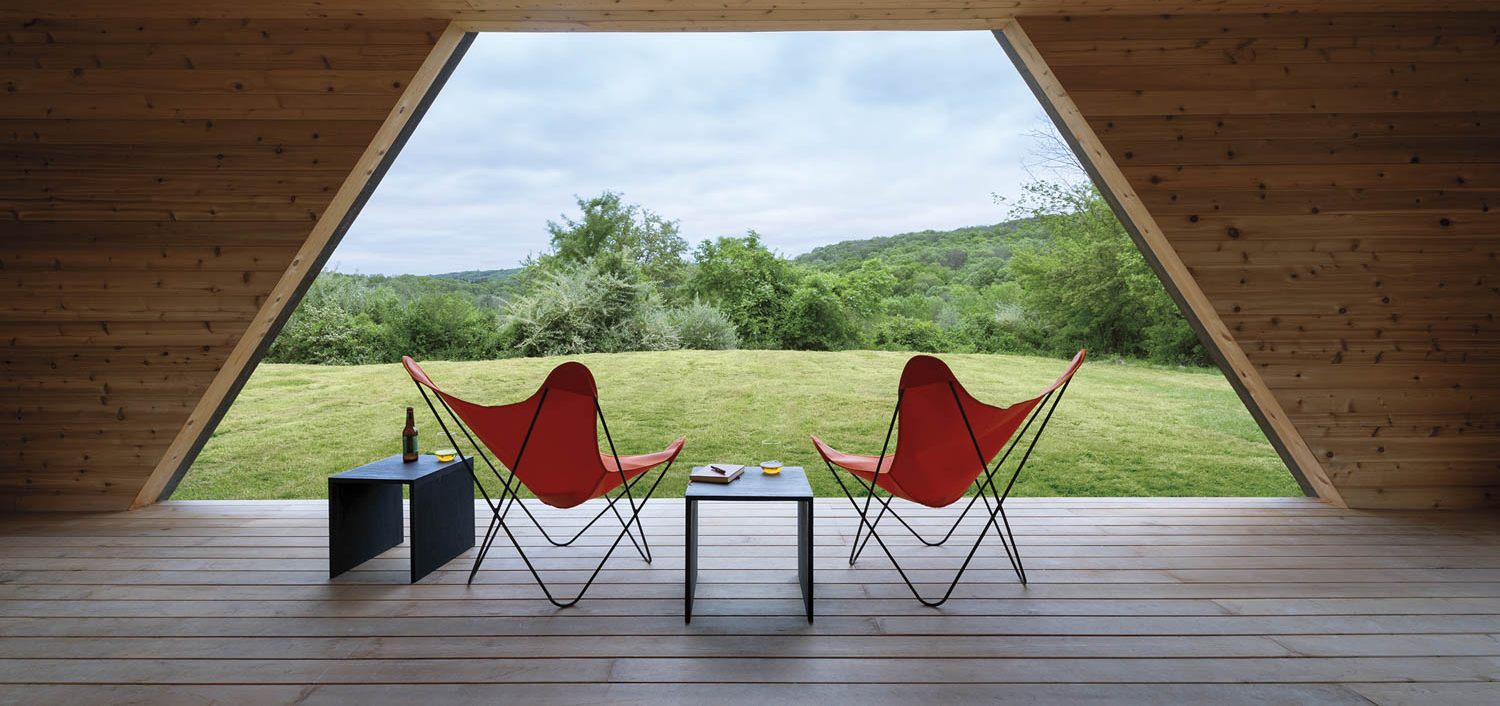 two red chairs sitting on deck with view of the landscape